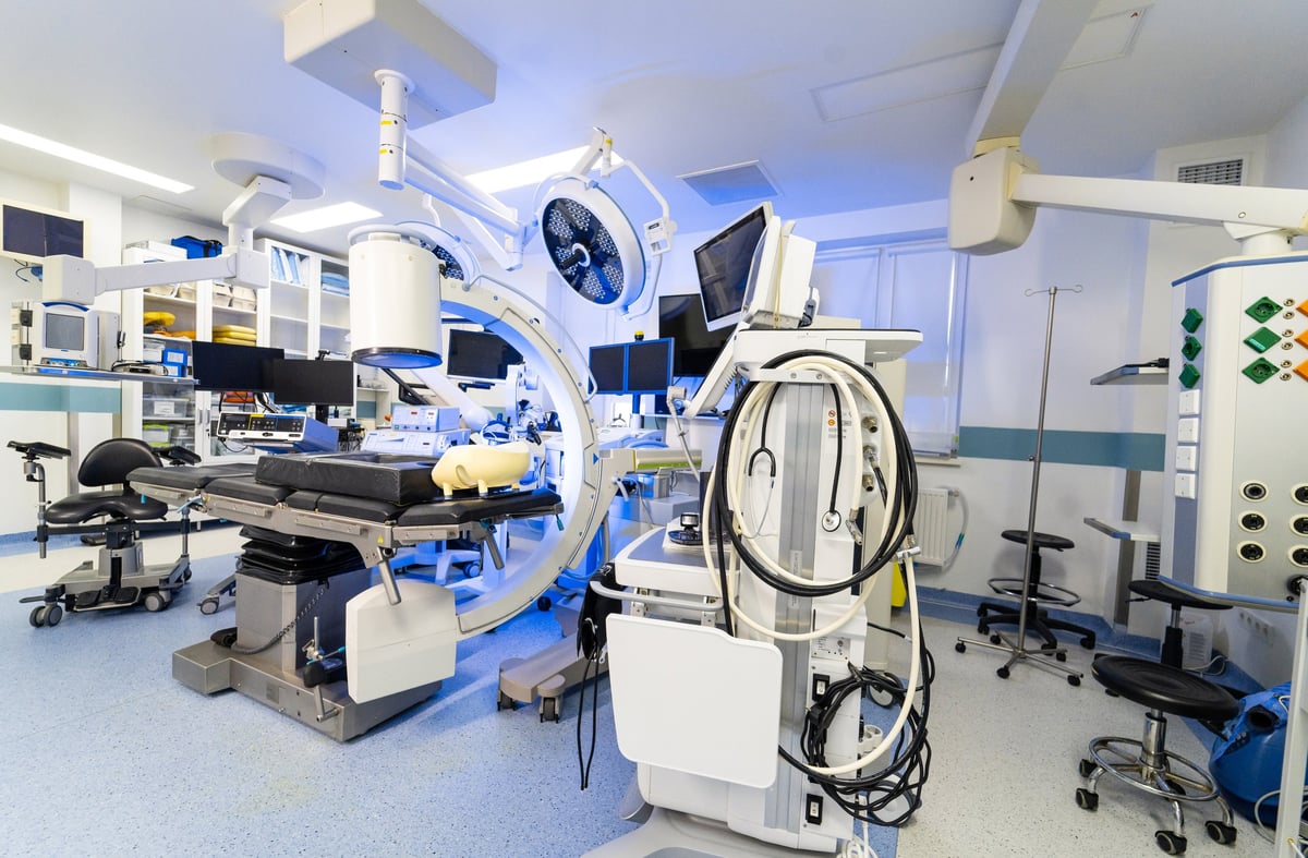 Modern hybrid operating room with C-arm fluoroscopy and medical monitors